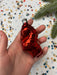 A hand holding a shiny red ornament against a background of colorful confetti.