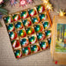 A box filled with colorful Christmas ornaments, including glass baubles and baubles with intricate designs, placed on a wooden surface with a handwritten note and a small picture frame.