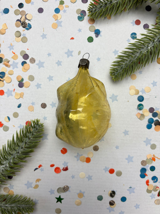a yellow ornament with a black base, surrounded by a scattering of colorful confetti and green pine branches.