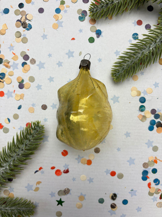 a yellow ornament with a black base, surrounded by a scattering of colorful confetti and green pine branches.
