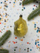 a yellow ornament with a black base, surrounded by a scattering of colorful confetti and green pine branches.