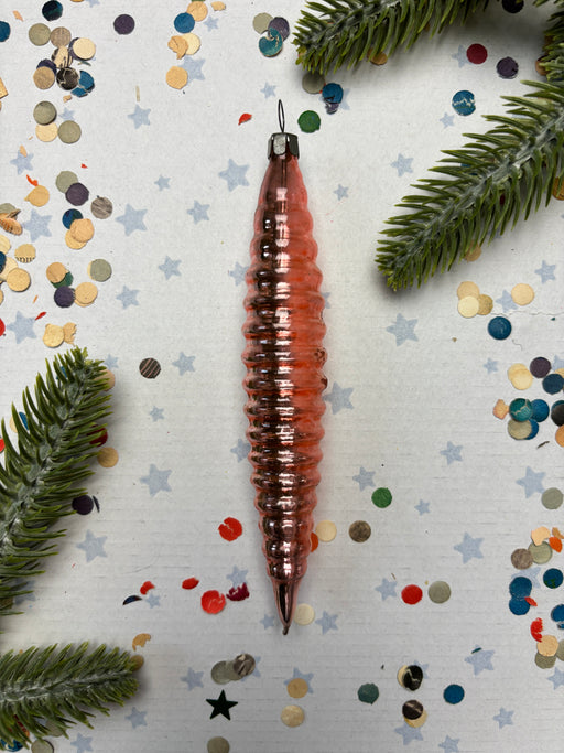 a Christmas ornament with a spiral design, surrounded by confetti and pine branches.