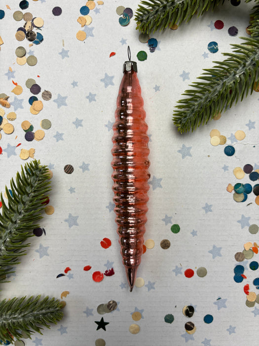 a Christmas ornament with a spiral design, surrounded by confetti and pine branches.