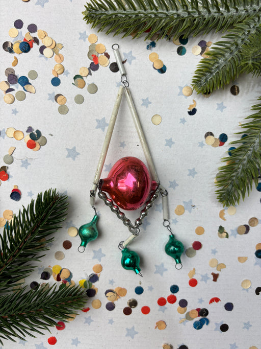 a festive scene with Christmas decorations, including a red ornament, green ornaments, and confetti scattered on a white background.