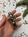 A hand holding a shiny, metallic ornament resembling a bear or a similar animal shape, with a background of colorful confetti or small circles.