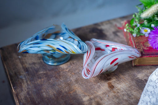 two glass bowls with colorful, swirling patterns on a wooden surface.