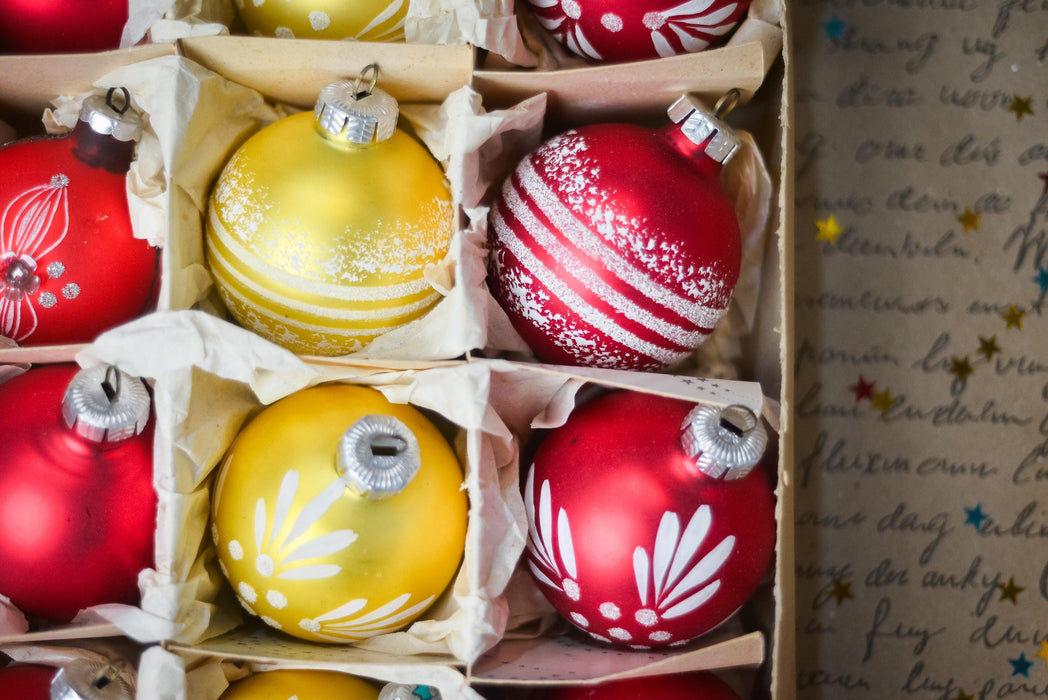 A close-up view of a collection of colorful Christmas ornaments, including red, yellow, and white ornaments, arranged in a box.