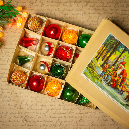 A box filled with various Christmas ornaments, including red, green, and yellow balls, as well as a picture of Santa Claus and reindeer.