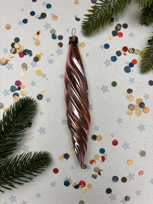 a twisted metallic ornament with a spiral shape, surrounded by colorful confetti and pine branches.