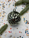 a shiny silver ornament with a reflective surface, surrounded by colorful confetti and green pine branches.