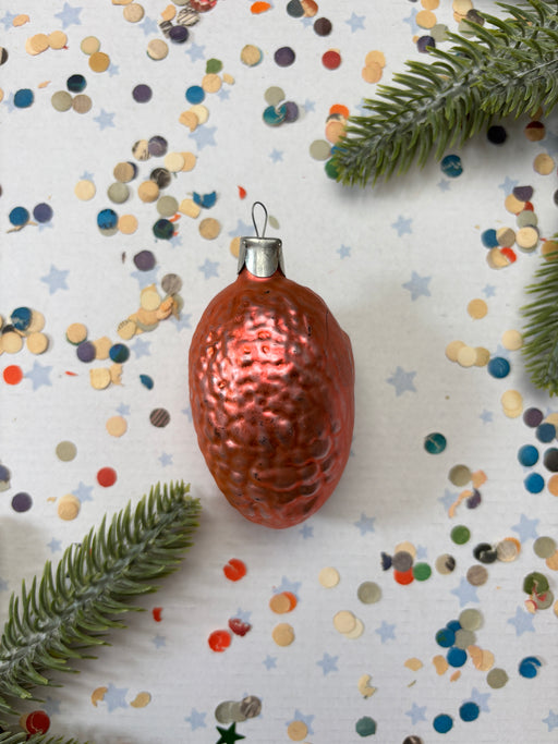 A shiny, metallic ornament in the shape of a brain is surrounded by colorful confetti and a sprig of greenery on a white background.
