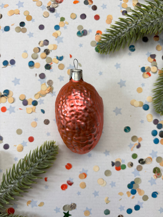 A shiny, metallic ornament in the shape of a brain is surrounded by colorful confetti and a sprig of greenery on a white background.