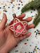 A hand holding a pink star-shaped ornament with a star design, surrounded by colorful confetti on a festive background.