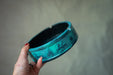 A hand holding a blue ashtray with a decorative design on it.