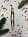 a shiny gold ornament with a pointed end, surrounded by colorful confetti and pine branches.