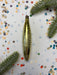 a shiny, metallic object, possibly a piece of jewelry or a decorative item, placed on a background of confetti and green leaves.