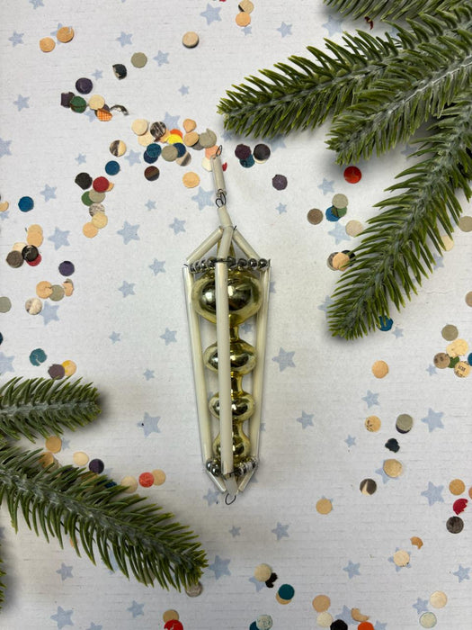 a decorative ornament with three spherical objects, surrounded by a scattering of colorful confetti and pine branches.