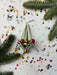 a festive scene with a Christmas ornament, confetti, and pine branches.