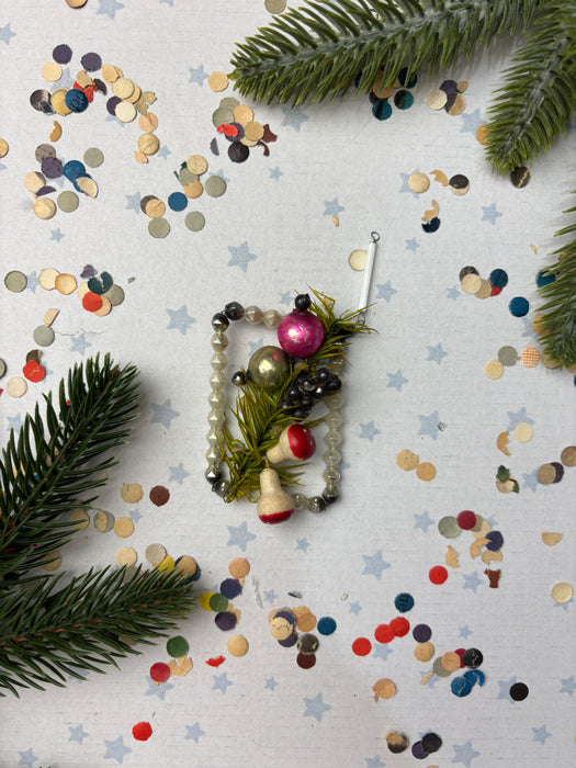a festive scene with Christmas decorations, including a Christmas tree branch, ornaments, and confetti scattered across a white background.