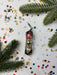 a Christmas ornament with three glass balls, surrounded by confetti and pine branches.