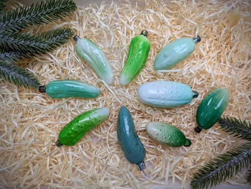 A collection of green and white glass or ceramic objects, including small figurines or ornaments, arranged on a bed of straw or hay.