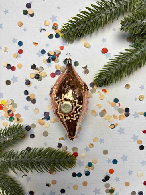 a Christmas ornament with a star design, surrounded by confetti and pine branches.