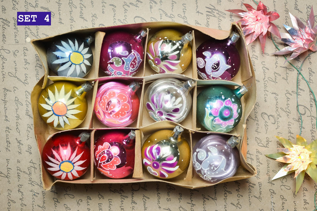A set of twelve colorful Christmas ornaments arranged in a cardboard box, with some ornaments featuring intricate designs and patterns.