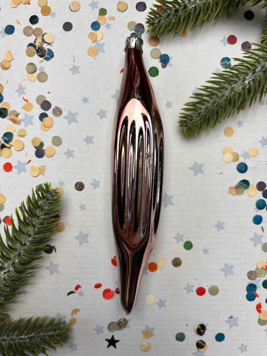 a shiny metallic ornament, possibly a Christmas ornament, placed on a background of colorful confetti and pine branches.
