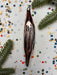 a shiny metallic ornament, possibly a Christmas ornament, placed on a background of colorful confetti and pine branches.