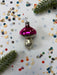 a pink ornament with white polka dots, surrounded by scattered confetti and a sprig of greenery.