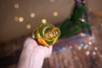 A hand holding a glass bottle with a golden-colored liquid, against a blurred background with colorful lights.