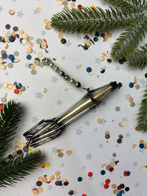a metallic object with a curved shape, surrounded by confetti and pine branches.