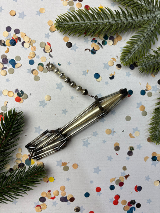 a metallic object with a curved shape, surrounded by confetti and pine branches.