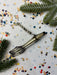 a metallic object with a curved shape, surrounded by confetti and pine branches.