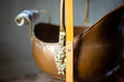 A close-up image of a brass bowl with a decorative handle, featuring a ruler for scale.