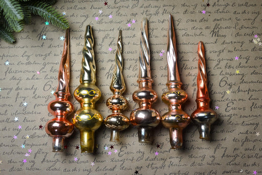 a collection of ornate Christmas ornaments, including golden and copper-colored pieces, arranged on a background with handwritten text.