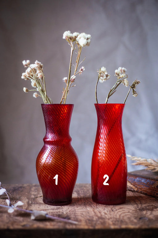 Two red vases with white flowers are placed on a wooden surface, with the number 1 and 2 visible on the vases.