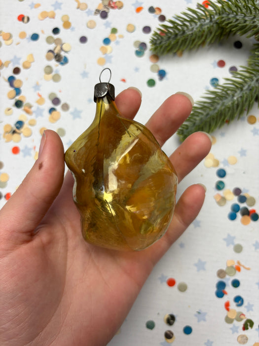 A hand holding a golden ornament against a background of colorful confetti.
