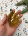 A hand holding a golden ornament against a background of colorful confetti.