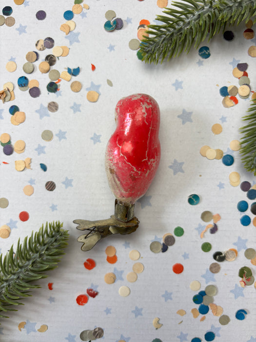a red object, possibly a toy or ornament, surrounded by confetti and a green plant.