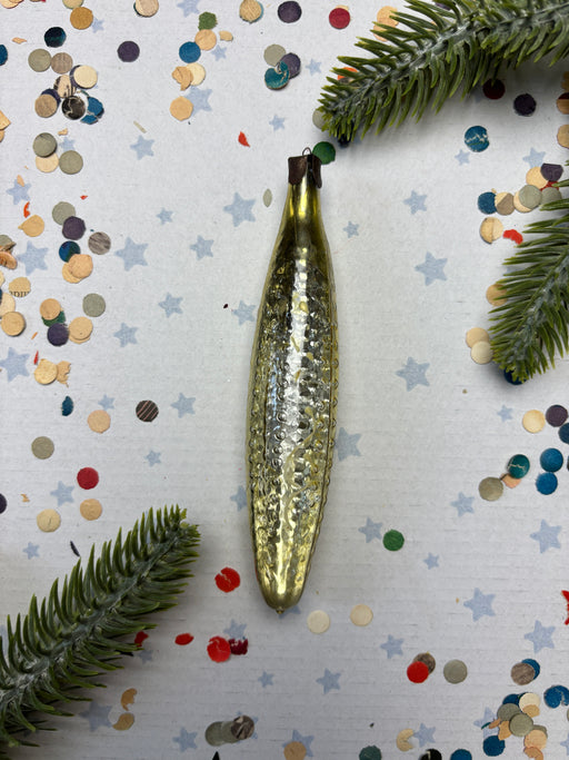 a shiny, metallic ornament with a textured surface, surrounded by confetti and pine branches.