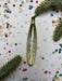 a shiny, metallic ornament with a textured surface, surrounded by confetti and pine branches.