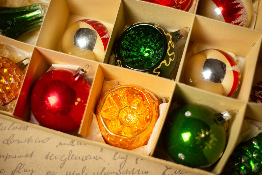 A close-up view of a collection of Christmas ornaments in a box, with various colors and designs.