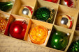 A close-up view of a collection of Christmas ornaments in a box, with various colors and designs.