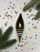 a green ornament with white stripes, surrounded by colorful confetti and pine branches.