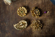 four ornate gold brooches or pins arranged on a wooden surface.