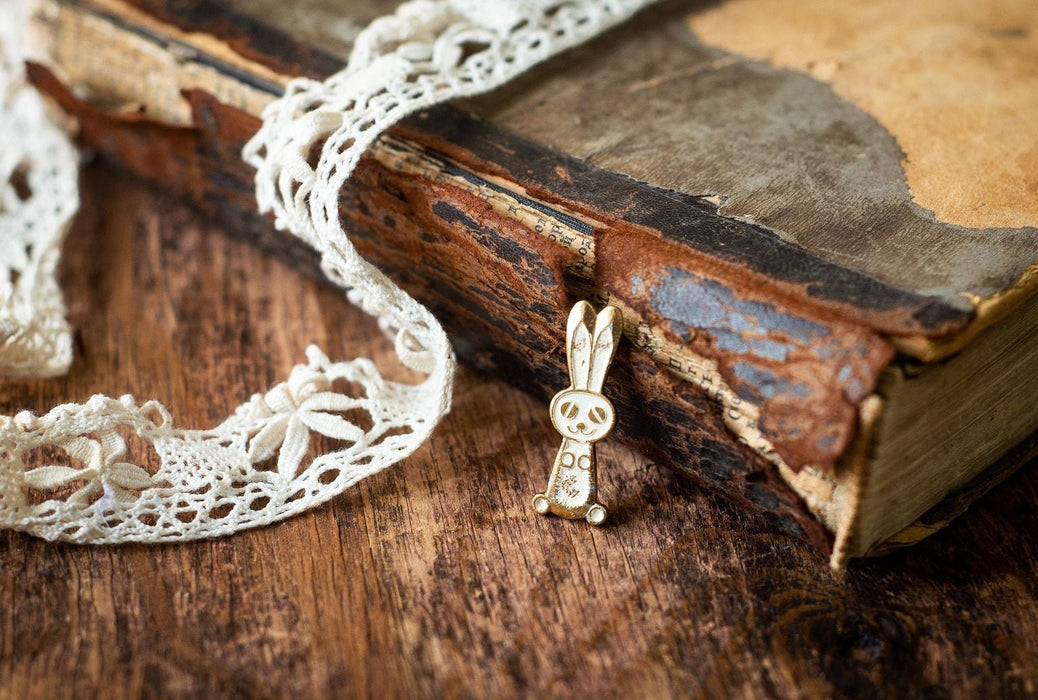 An old, worn book with a white lace doily lying next to it on a wooden surface.