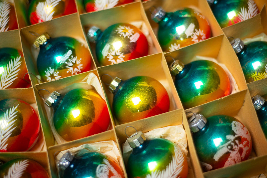 A close-up view of a collection of colorful Christmas ornaments arranged in a grid-like pattern, with each ornament placed in a wooden box.
