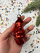 A hand holding a shiny red ornament against a background of colorful confetti.