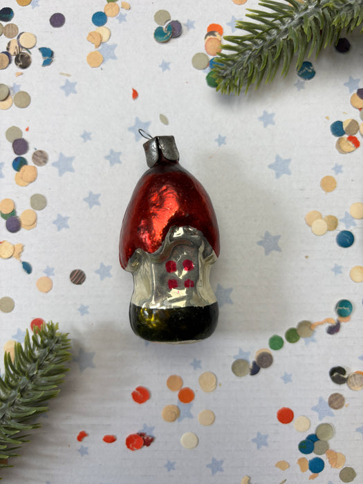 a red ornament with a black base, surrounded by scattered confetti and a green pine branch.